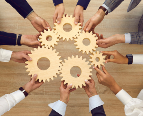 A group of people holding interlocking gears symbolizing teamwork and collaboration, representing the integration and efficiency benefits of Dallas VoIP solutions.