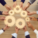 A group of people holding interlocking gears symbolizing teamwork and collaboration, representing the integration and efficiency benefits of Dallas VoIP solutions.