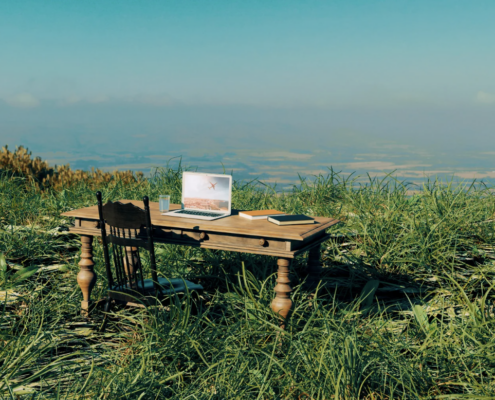 A remote work setup with a laptop on a wooden desk in nature, representing flexible work solutions supported by business continuity planning Dallas for secure and seamless operations.